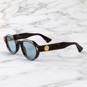 An image of the Palace Cutler and Gross Victory Round Sunglasses in Havana frame side view with arms open marble background