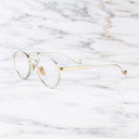 An image of the Lennox 1428 Round Opticals in Silver/Gold frame side view with arms open marble background