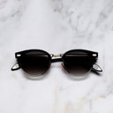 An image of the Breitling Biarritz 0003 Round Sunglasses in Black frame frontal view with arms closed marble background