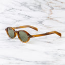 An image of the GR13 Oval Sunglasses in Mustard Horn frame side view with arms open marble background