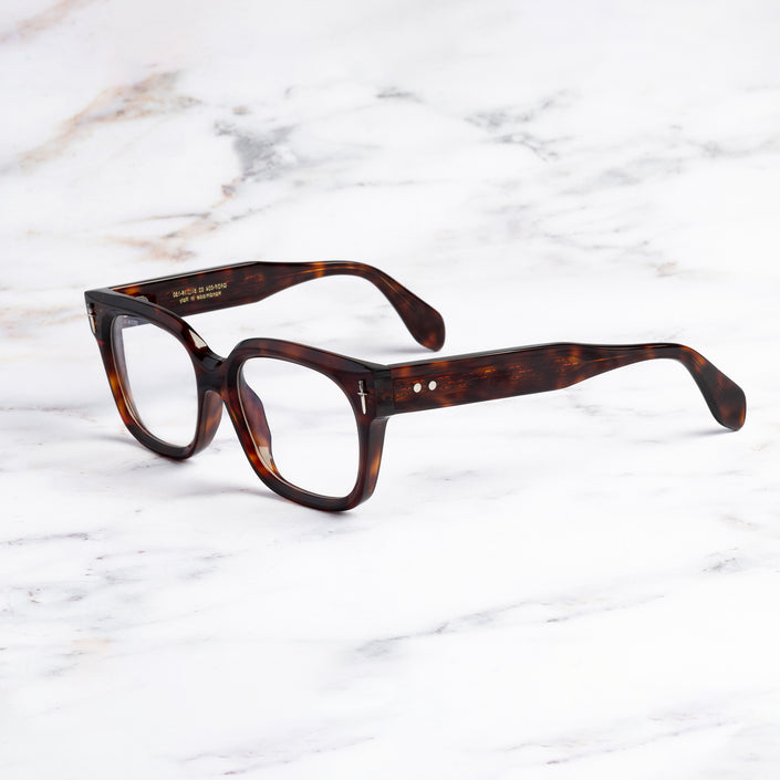 An image of the The Great Frog Kim Square Optical Glasses in Dark Turtle frame side view with arms open marble background