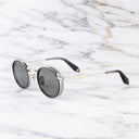 An image of the Breitling Chrono 0002 Round Sunglasses Dark Grey frame side view with arms open marble background