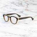 An image of the Cutler and Gross 9290 Round Horn Optical in Smoke Brown/Cream Buffalo Horn frame side view with arms open marble background