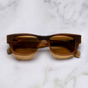 An image of the Cutler and Gross 0425 Rectangular Horn Sunglass in Toasted Brown Buffalo Horn frame frontal view with arms closed marble background