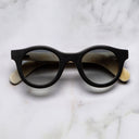 An image of the Cutler and Gross 0737 Round Horn Sunglass in Deep Matte Black/Cream Buffalo Horn frame frontal view with arms closed marble background