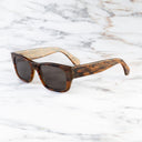 An image of the Cutler and Gross 1214 Rectangular Horn Sunglass in Speckled Brown Buffalo Horn frame side view with arms open marble background