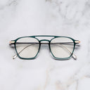 An image of the 0009 Aviator Opticals in Gradient Green on 18K Rose Gold + 18K Rhodium frame frontal view with arms closed marble background