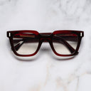 An image of the 1305 Square Opticals in Burgundy frame frontal view with arms closed marble background