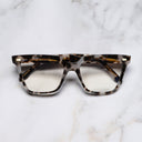 An image of the 1346 Cat Eye Opticals in Jet Engine Grey frame frontal view with arms closed marble background