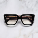 An image of the 1401 Cat Eye Opticals Black frame frontal view with arms closed Marble background