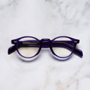 An image of the GR04 Round Optical Glasses in Ink frame frontal view with arms closed marble background