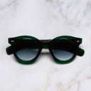 An image of the 1390 Round Sunglasses in Emerald Colour Studio frame frontal view with arms closed marble background