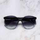 An image of the 1395 Round Sunglasses in Black Beauty frame frontal view with arms closed marble background