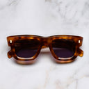 An image of the 1402 D-Frame Acetate Sunglasses in Tortoiseshell frame frontal view with arms closed marble background