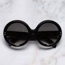 An image of the 1412 Round Sunglasses in Black on Oil frame frontal view with arms closed marble background