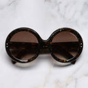 An image of the 1412 Round Sunglasses in Brush Stroke frame frontal view with arms closed marble background