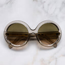 An image of the 1412 Round Sunglasses in Sand Crystal frame frontal view with arms closed marble background