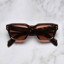 An image of the 1432 Square Sunglasses in Dark Havana frame frontal view with arms closed marble background