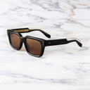 An image of the Cutler and Gross 1434 Square Sunglass in Black frame side view with arms open in marble background.