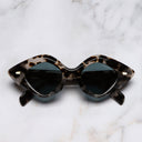 An image of the 9126 Oversize Sunglasses in Jet Engine Grey frame side view with arms closed marble background