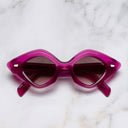 An image of the 9126 Oversize Sunglasses in Fuchsia frame side view with arms closed marble background