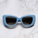 An image of the 9797 Cat-Eye Sunglasses in Solid Light Blue frame frontal view with arms closed marble background