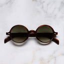An image of the GR01 Round Sunglasses in Multi Havana Aubergine frame frontal view with arms closed marble background