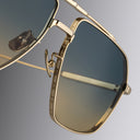 Cutler and Gross Gold-framed sunglasses with a gradient lens on a gray background