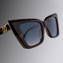 An image of the Cutler and Gross Valentina 002 Cat Eye Sunglasses in tortoiseshell frame detail close up from right side view with gold logo in temples.