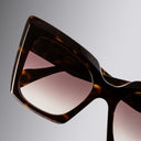 Tortoiseshell sunglasses with gradient lenses on a gray background