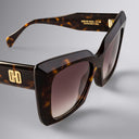 Sunglasses with tortoiseshell frame and brown gradient lenses on a gray background