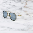 An image of the Cutler and Gross The Great Frog Limited-Edition Triumph Aviator Sunglasses in Silver/Olive frame side view with arms open marble background.
