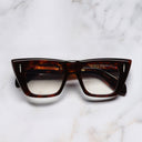 An image of the The Great Frog Love And Death Cat Eye Glasses in Dark Turtle frame frontal view with arms closed marble background