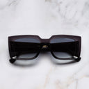 An image of the The Great Frog Mini Reaper Square Sunglasses in Dark Grey frame frontal view with arms closed marble background