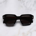 An image of the The Great Frog Bones Link Rectangle Sunglasses in Black frame frontal view with arms closed marble background