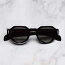 An image of the The Great Frog Lucky Diamond I Round Sunglasses in Black
 frame frontal view with arms closed marble background