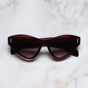 An image of the The Great Frog Mini Cat Eye Sunglasses in Bordeaux frame frontal view with arms closed marble background