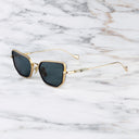 An image of the Cutler and Gross The Great Frog Paisley Cat Eye Sunglasses in Gold/Dark Grey frame side view with arms open marble background.