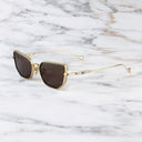 An image of the Cutler and Gross The Great Frog Paisley Cat Eye Sunglasses in Gold/Olive frame side view with arms open marble background.
