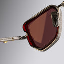 An image of the Cutler and Gross The Great Frog Paisley Cat Eye Sunglasses in Gun Metal/Bordeaux frame detail close up of left lens and temple.