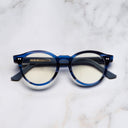 An image of the 1378 Blue Light Filter Optical Round Glasses (Small) in Striped Blue Havana on Powder Blue frame frontal view with arms closed marble background