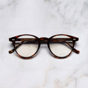 An image of the 0710 Kingsman Optical Round Glasses in Dark Turtle frame frontal view with arms closed marble background