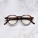 An image of the 1313 Kingsman Optical Round Glasses in Dark Turtle frame frontal view with arms closed marble background