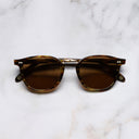 An image of the 1007 Kingsman Round Sunglasses in Brown Amber Tortoise frame frontal view with arms closed marble background