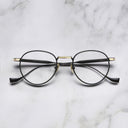 An image of the Lennox 1428 Round Opticals in Black/Gold frame frontal view with arms closed marble background