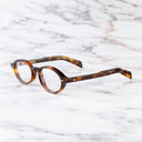 An image of the GR13 Oval Opticals in Havana frame side view with arms open marble background
