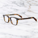 An image of the GR10 Square Opticals in Multi Havana frame side view with arms open marble background
