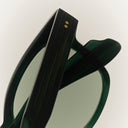 An image of Cutler and Gross frame in Black colourway presented sideways with arms closed, showing details on the temple and right dark green lens.