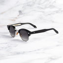 An image of the Breitling Biarritz 0003 Round Sunglasses in Black frame side view with arms open marble background