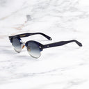 An image of the Breitling Biarritz 0003 Round Sunglasses in Classic Navy Blue frame side view with arms open marble background